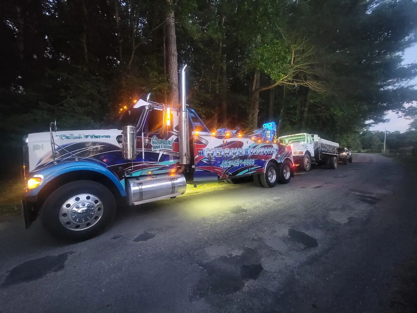 Towing a dump truck at dusk with the light bar on