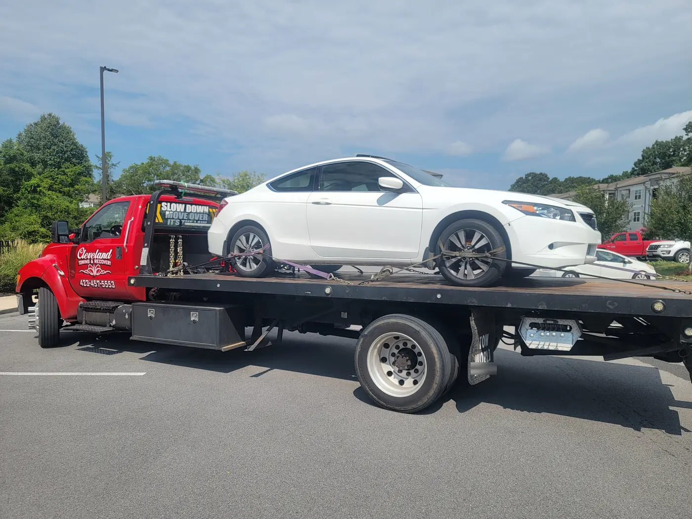 A sedan strapped down on the deck in an apartment parking lot