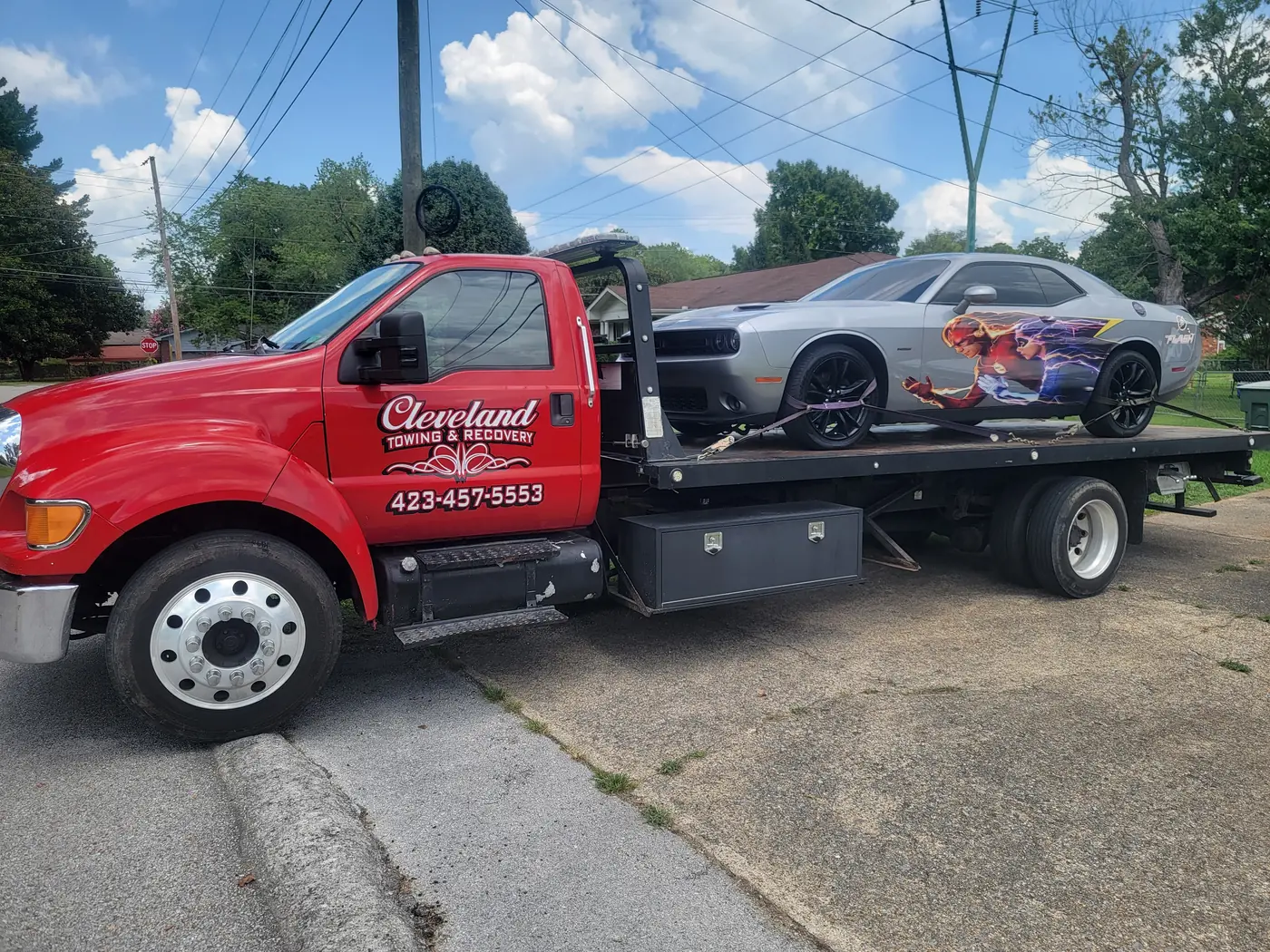 A muscle car strapped down on our rollback deck with all four wheels off the road
