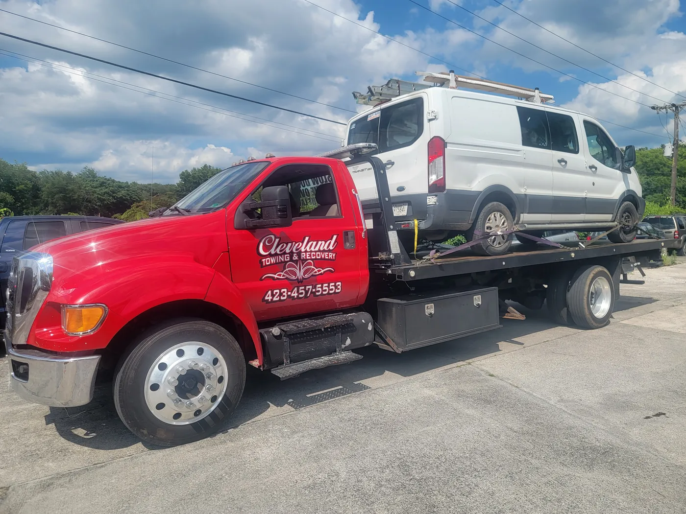 A commercial cargo van with a roof ladder rack loaded on our rollback deck