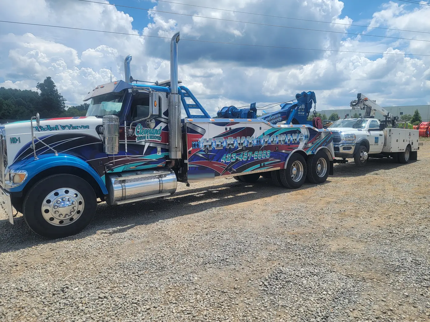 Our heavy wrecker hooked to a white utility service truck in the yard